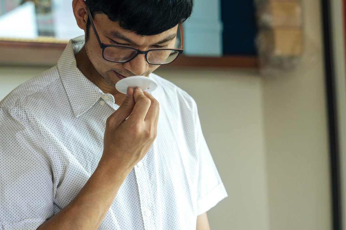 Kuo Ching-Wei smelling the lid of the tea cup to discern the scent.