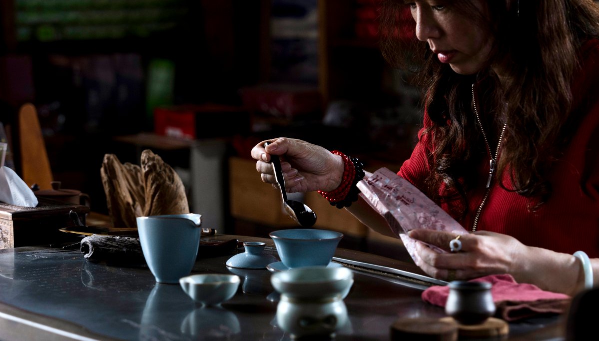 A woman at the tea table ready to brew tea.