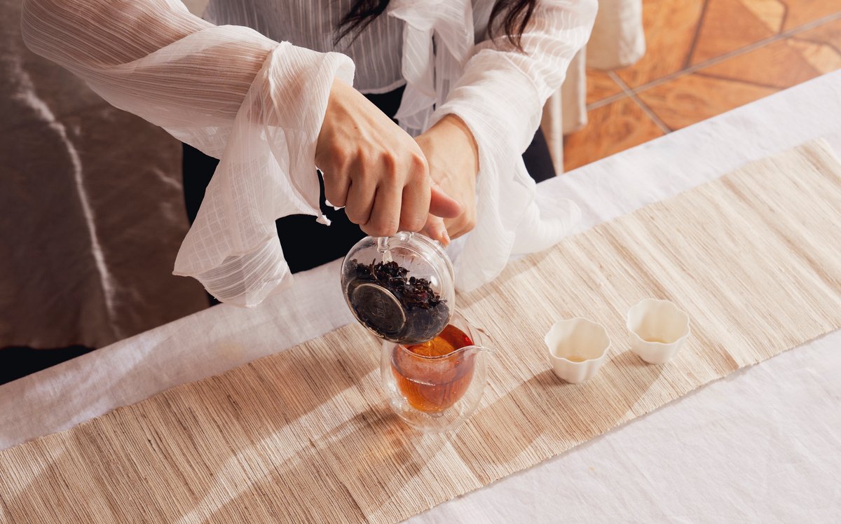 Red Oolong tea is being poured our from a transparent tea pot.