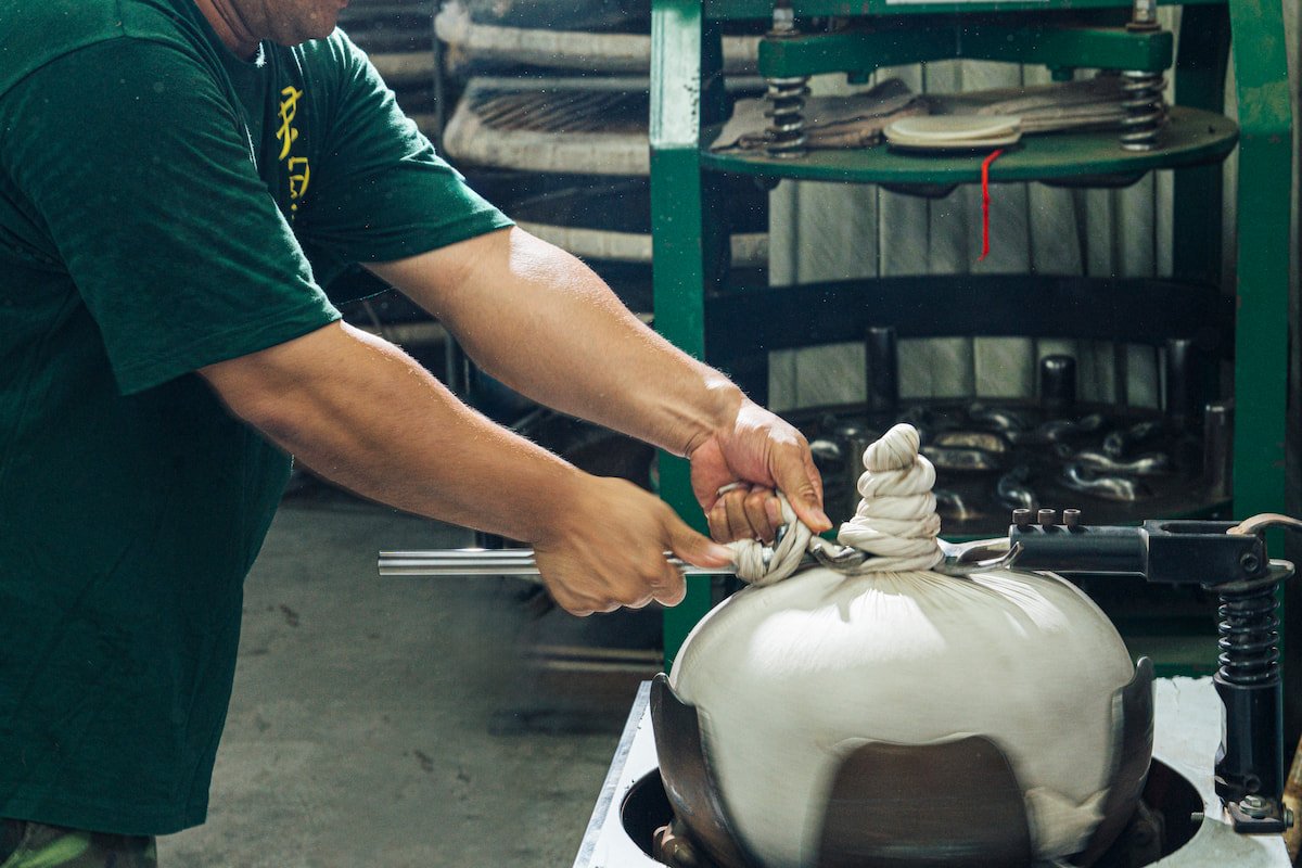 製茶師操作包布團揉機器.
