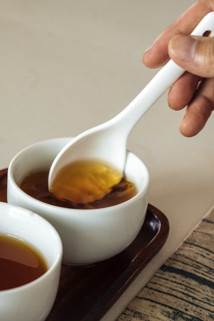一隻白色的茶杓緩緩的攪動琥珀色的茶湯.