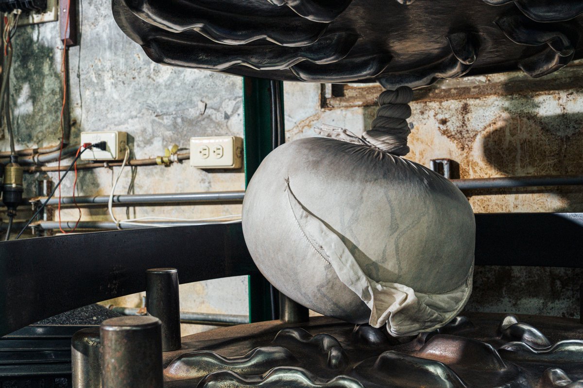 A giant clothed tea ball on the canvas wrapped-rolling machine.