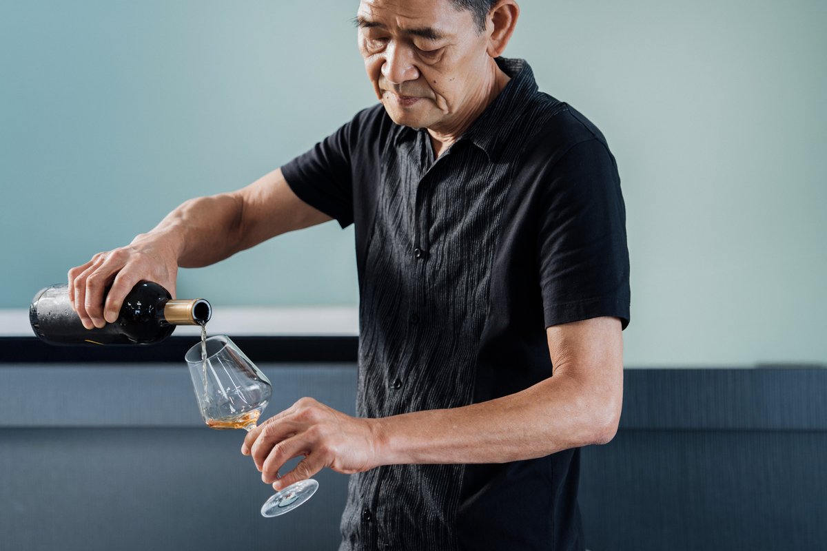 A man pouring Red Oolong tea from a wine bottle.