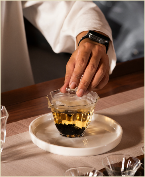 Tea leaves being brewed in a transparent gaiwan.